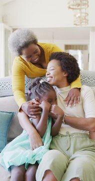 Vertical video of african american mother, daughter and grandmother embracing at home, slow motion
