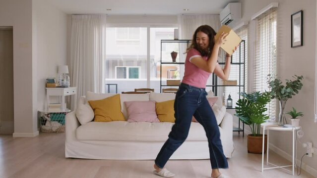 Asia people young Gen Z woman smile carry parcel box goods carton packaging happy joy fun dance at home. Omni channel enjoy buy gift order postal at retail online shop store fast courier send service.