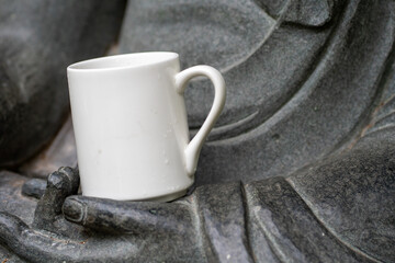White mug, mock up, empty space for artwork, text, standing on stone, outdoors, green grass, trees, sky in the background, soft sunlight, nature