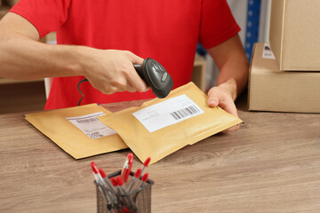 Post office worker with scanner reading parcel barcode at counter, closeup