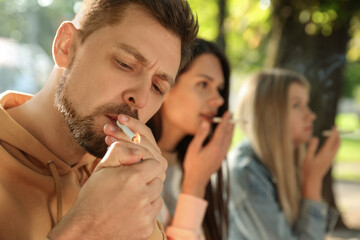 People smoking cigarettes outdoors on sunny day