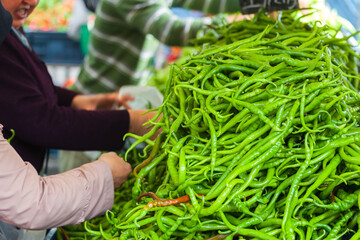 market stall with a bulk of green chili peppers