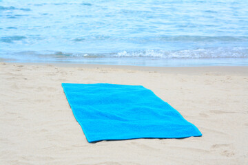 Blue towel on sandy beach near sea