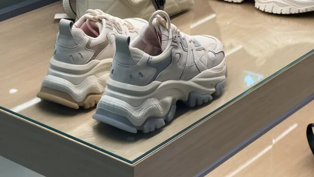 White women's sneakers stand in the shoe store window