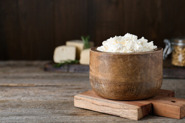 Delicious tofu cream cheese in bowl on wooden table, space for text
