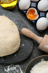 Fresh yeast dough and ingredients on black table, flat lay