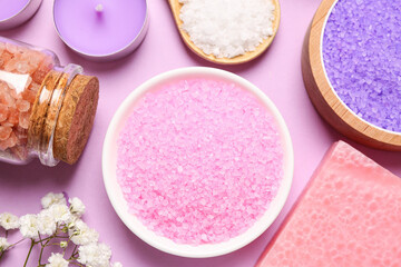 Sea salt and different spa products on pink background, flat lay