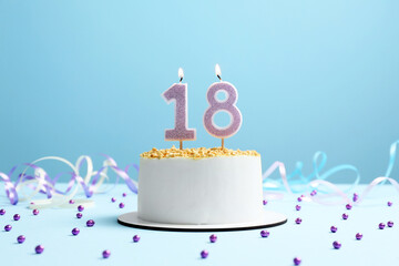 Coming of age party - 18th birthday. Delicious cake with number shaped candles on light blue...