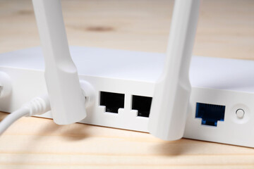New white Wi-Fi router on wooden table, closeup