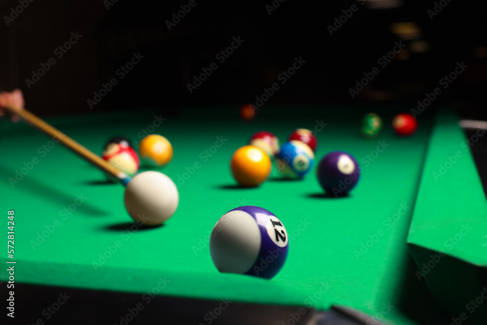 Sticker Many colorful billiard balls and cue on green table, closeup. Space for text