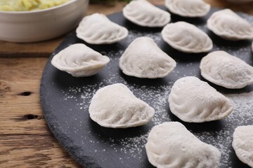 Fototapeta na wymiar Raw dumplings (varenyky) on wooden table, closeup