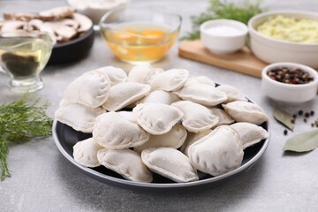 Raw dumplings (varenyky) and ingredients on grey table