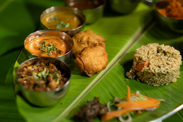 A vibrant Andhra-region meal plate with diverse vegetarian dishes, featuring fried potato dumplings ('aloo bajji') and spiced rice ('donne biryani') from southern India.