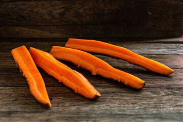 Sliced raw sweet carrots on a wooden kitchen table.