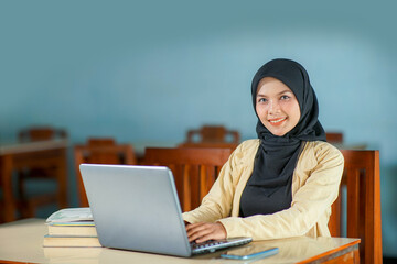 beautiful asian young woman wearing hijab smiling and look at camera at work, typing operating...