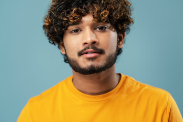 Cropped portrait of a hipster Indian man in yellow t-shirt, confidently looking at camera, over...
