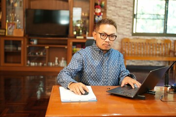 Striped shirt, wearing glasses, sitting and working in the office