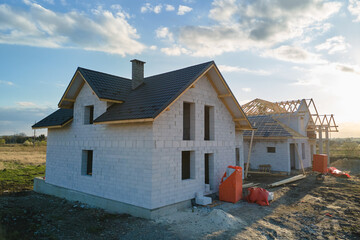 Aerial view of unfinished house with aerated lightweight concrete walls and wooden roof frame covered with metallic tiles under construction