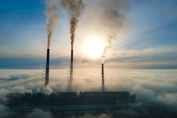 Coal power plant high pipes with black smoke moving upwards polluting atmosphere. Production of electrical energy with fossil fuel concept