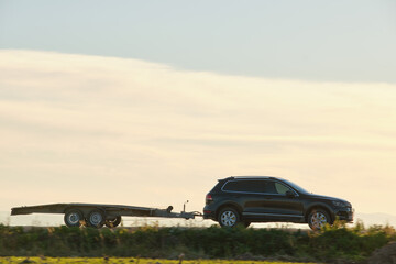 Tow truck vehicle with car transporting carrier trailer driving on highway in evening © bilanol