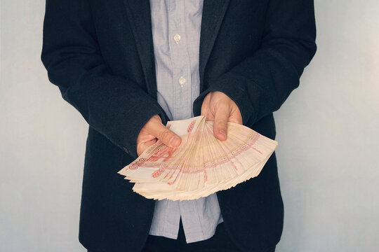 a large wad of money with a million rubles in the hand of a successful young man. businessman thinks of profit. Money raised from the sale of property. Russian banknotes rubles in hand
