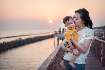 Fototapeta premium happiness travel baby and mom sunset water atmosphere on sea ,asian baby and mother travel outdoor