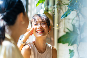 Happy Asian mother and daughter sitting by the window in coffee shop with drinking coffee and eating cake together. Happy family enjoy outdoor lifestyle shopping in the city on summer holiday vacation