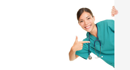 Medical sign person - woman showing blank poster billboard pointing. Young female nurse or medical doctor professional in green scrubs smiling happy isolated cutout PNG on transparent background. - 572840826