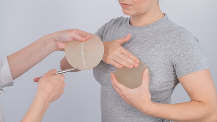 Caucasian woman trying on breast implants. A plastic surgeon helps a patient with a choice.