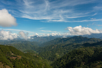 Aerial view of Mountains covered rainforest, trees and blue sky with clouds. Philippines.