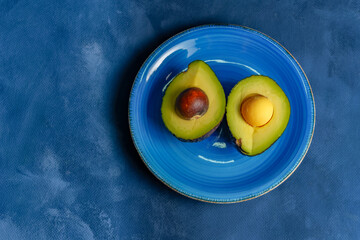 avocado cut in half in a blue plate