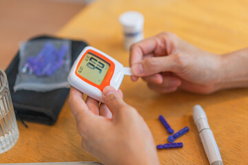 young woman using blood test kit at home while doing health check . home finger prick blood test . close up, diabetes concept, elderly health care,