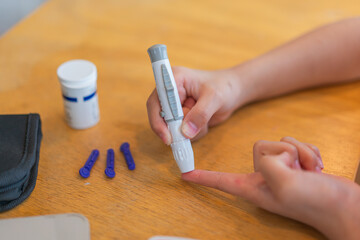 young girl using blood test kit at home while doing health check . home finger prick blood test . close up, diabetes concept, elderly health care,