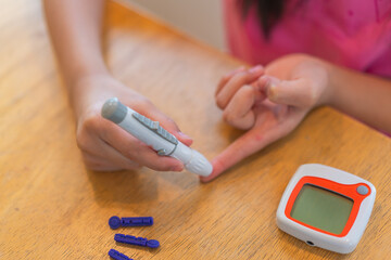 young girl using blood test kit at home while doing health check . home finger prick blood test . close up, diabetes concept, elderly health care,