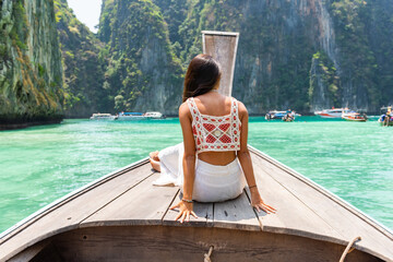 Happy Asian woman sitting on ship bow and looking beautiful nature of tropical island lagoon in...