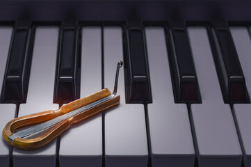 Ethnic jew's harp lies on the piano keys. The concept of the history of folk music and ancient...