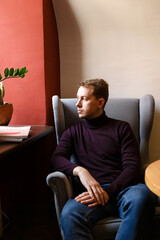 young man sits alone at a table with magazines