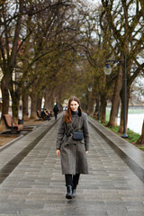 Fototapeta premium woman in a woolen coat walks alone in the middle of a spring city