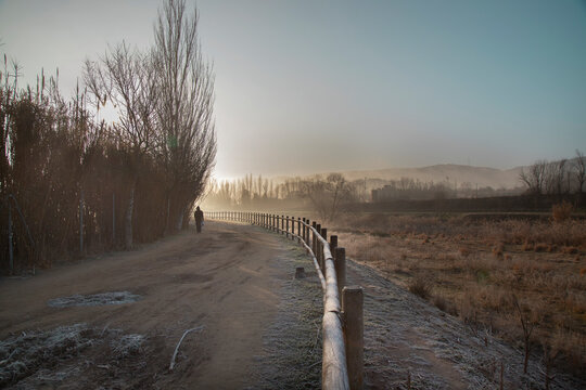 A man walking on a path in a misty morning