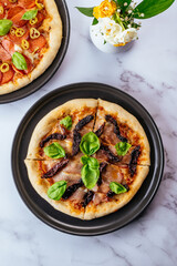 pizza with Parma ham and dried tomatoes on a marble table