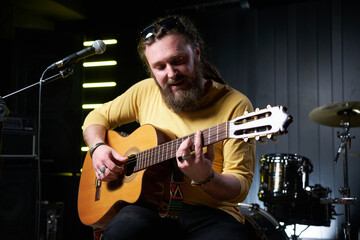 Guitarist man plays an acoustic guitar Close-up at studio