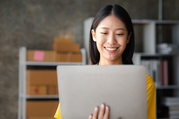 Naklejka premium The owner of an online store is checking orders for packaged products in order to prepare them for delivery to customers as ordered through the website. Online selling and online shopping concepts.