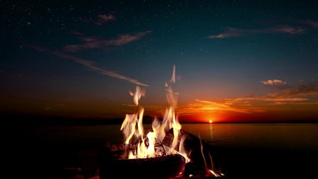 bonfire burns at night against the background of mountains and sea with bright stars
