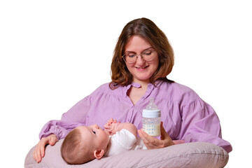 Woman mother feeds infant baby formula from a bottle, isolated on a white background. Kid aged six...