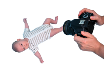 A photographer takes pictures of a newborn baby with a camera in studio, isolated on a white background. Photo session of children in the studio. Kid aged two months