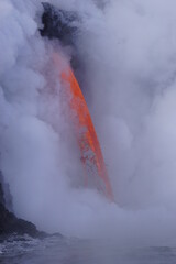 Stream of hot lava flowing down from high Cliff surrounded by white steam, Hawaii Big Island