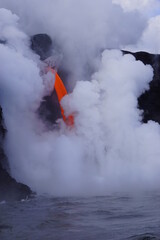 Lava flowing into the ocean from high cliff surrounded by white steam