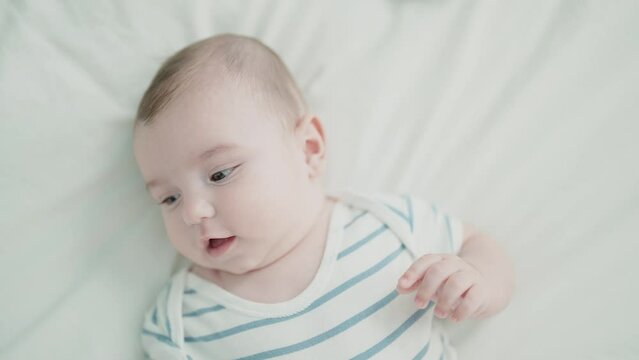 Adorable caucasian baby lying on bed with relaxed expression at bedroom