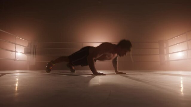 Portrait of a male athlete boosting his stamina and endurance while preparing for a sparring. Close-up view of professional boxer performing pushups and clapping in the air. High quality 4k footage