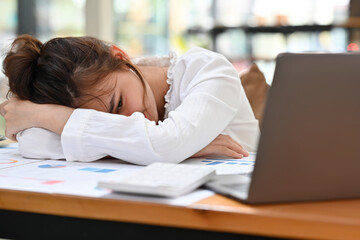 Overworked Caucasian Businesswoman lying on table, give up after hard day and dozing at her office desk.